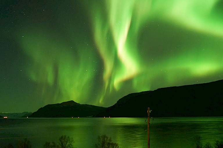 Aurora borealis boven de fjord bij de Arctic Panorama Lodge.