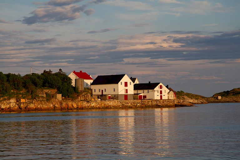 De ondergaande zon zorgt voor mooie kleuren op de huisjes aan het water.