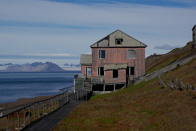 Een oud gebouw van Barentsburg met op de achtergrond de Esmarkgletsjer.